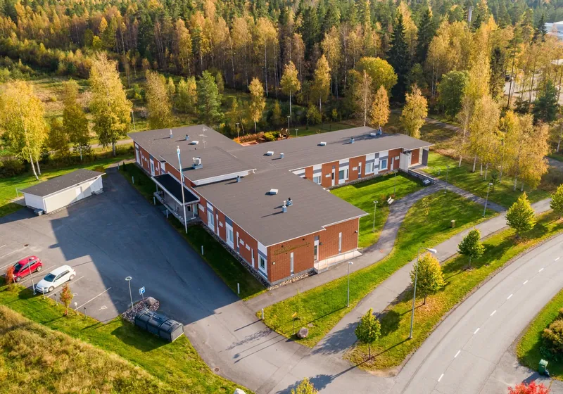 Kankaanpään yksikerroksinen tiilijulkisivuinen asumisyksikkö ilmasta kuvattuna syksyllä, ympärillä koivikkoa