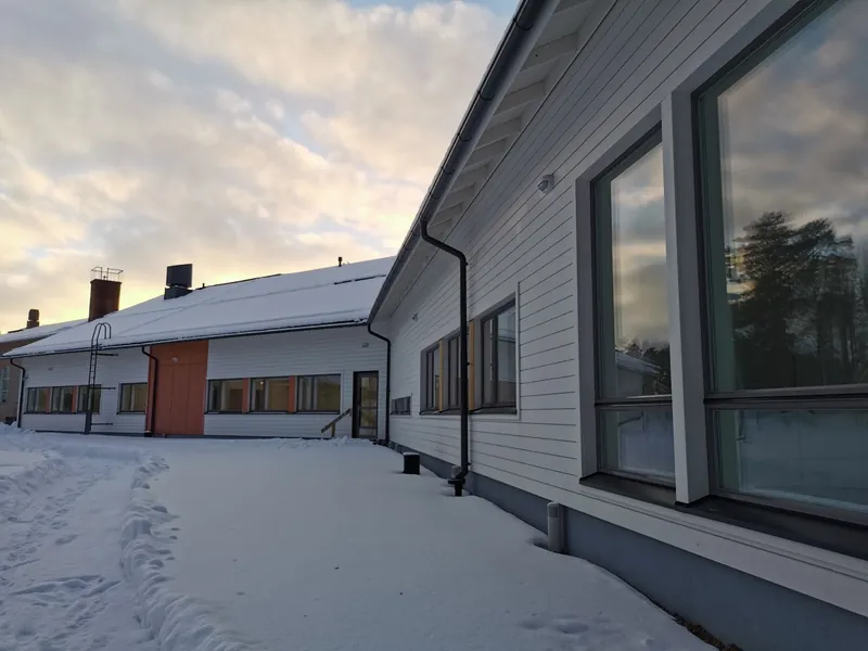 Honkajoen yhteiskoulun ja lukion vaaleaksi verhoiltu julkisivu talvella, lumista pihaa ja isot ikkunat